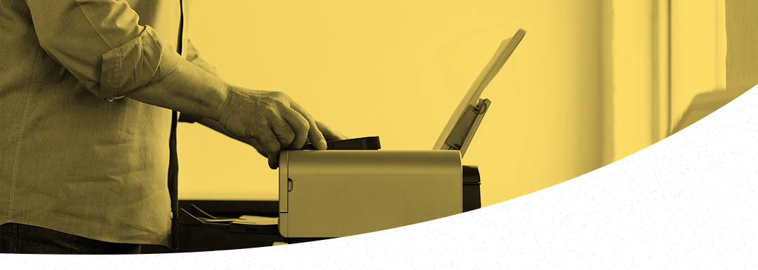 Person using a photocopier or printer, with hands operating the machine. The image has a yellow tint and the lower part features a white curved overlay, highlighting our high-quality refurbished printers in action.