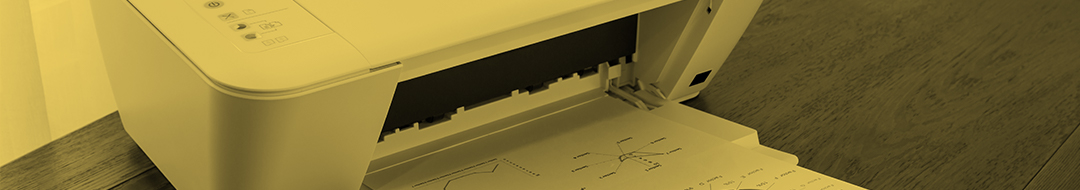 A refurbished printer on a wooden surface is printing a page with diagrams and charts. The image has a yellow tint.