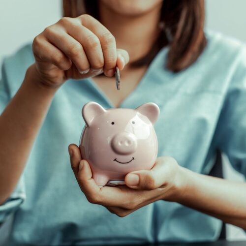 img of someone putting money in a piggy bank